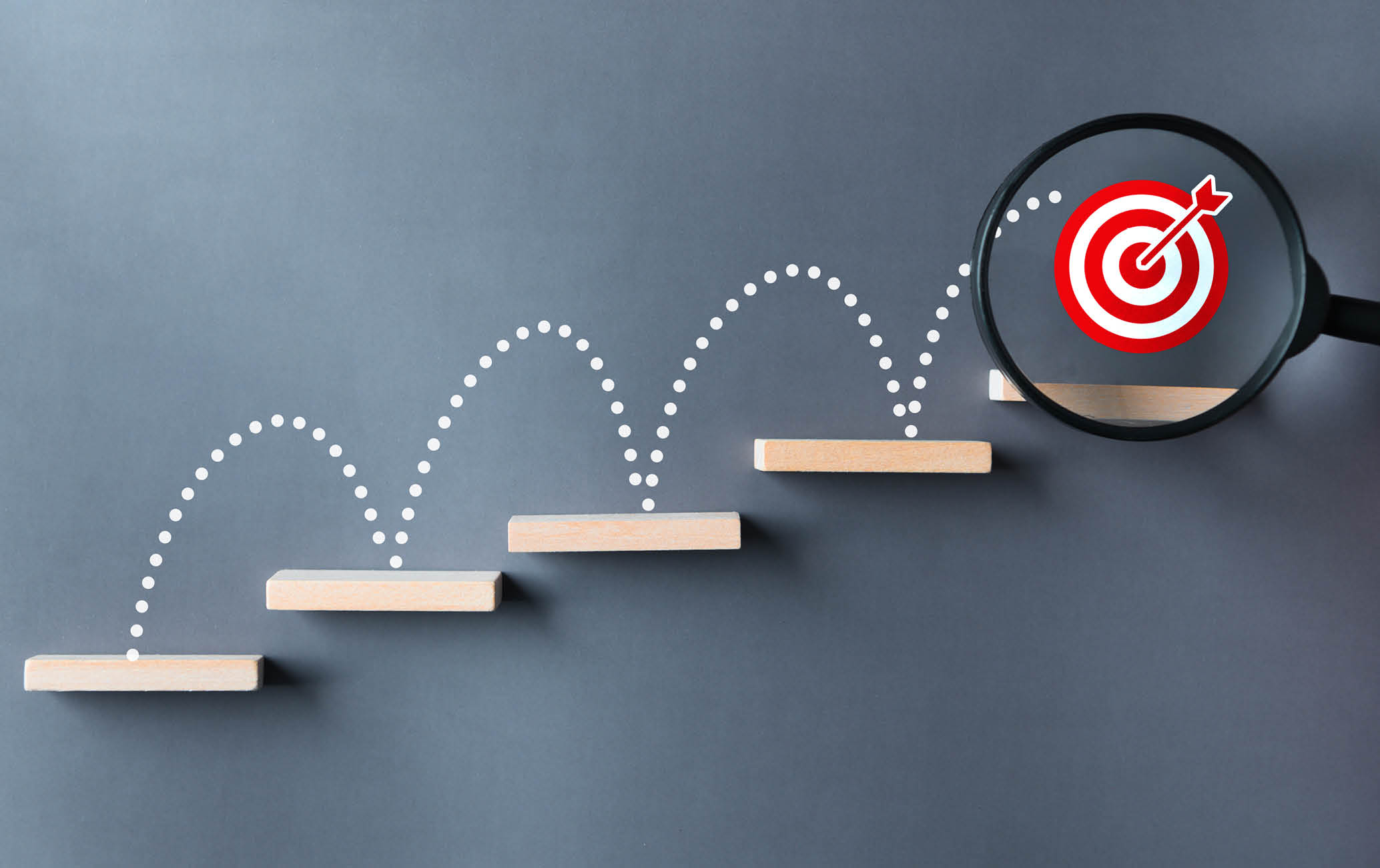 Unlock potential of business success stairs dart and dartboard targets magnifying glass with hand on gray background. Explore opportunities growth embrace steps to achieve ambitions and goal concept.
