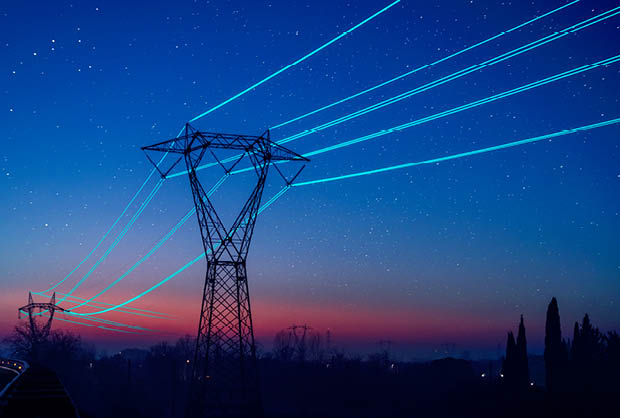 Electricity pilon with glowing cables over sunset sky