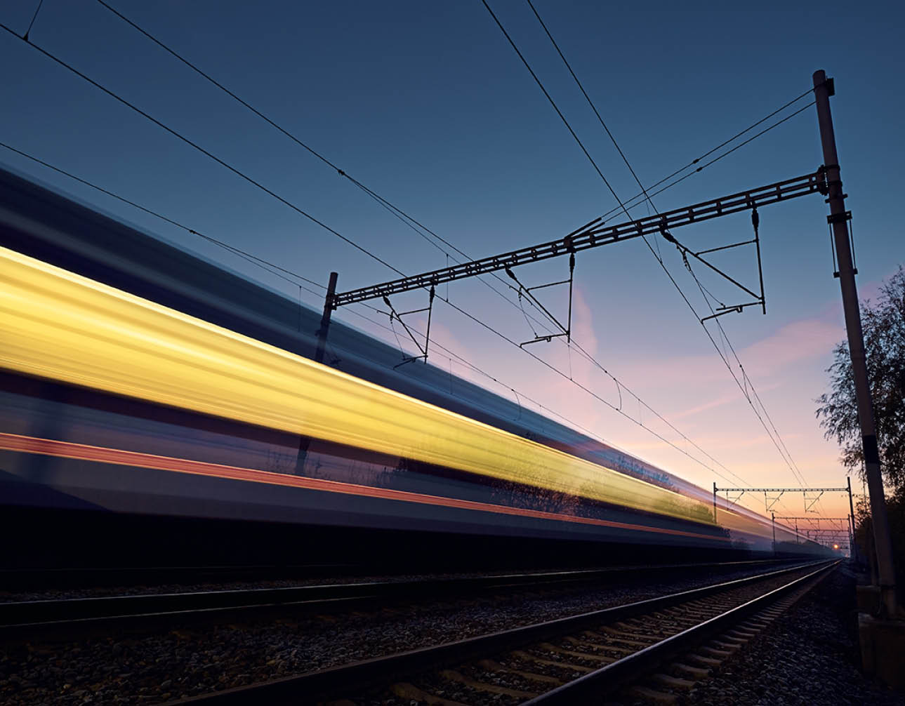 Railway at beautiful dawn. Long exposure of train on railroad track. Moving modern intercity passenger train.