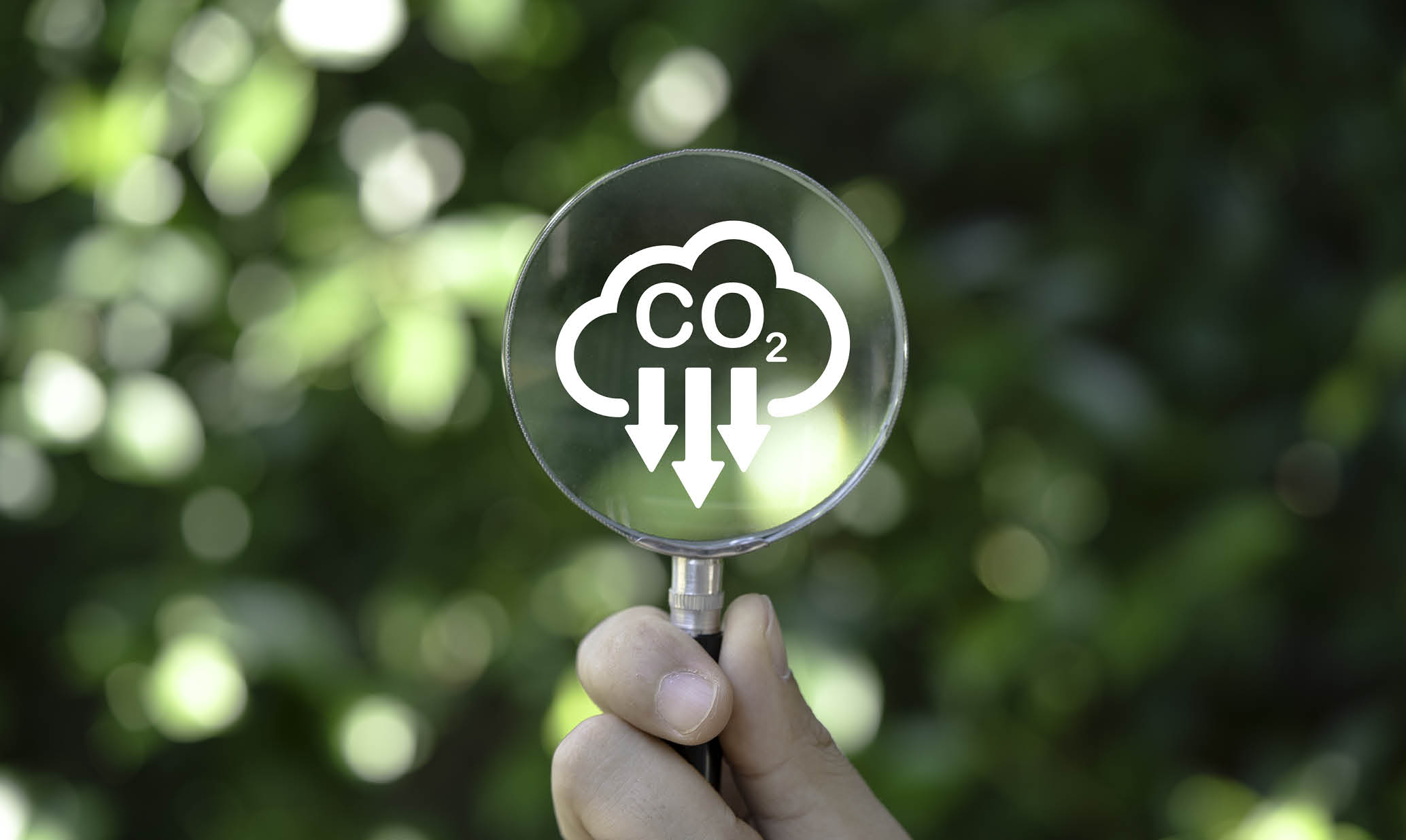 Hand holding magnifier glass with reduction carbon emission icon for zero carbon emission , CO2 carbon footprint and carbon credit to limit global warming within 2050 from Kyoto protocol concept.